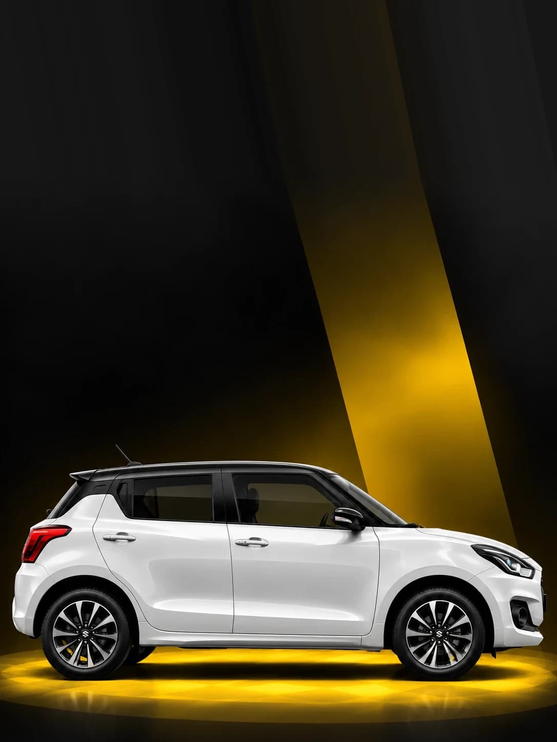 White Maruti Suzuki Swift hatchback under a yellow spotlight
