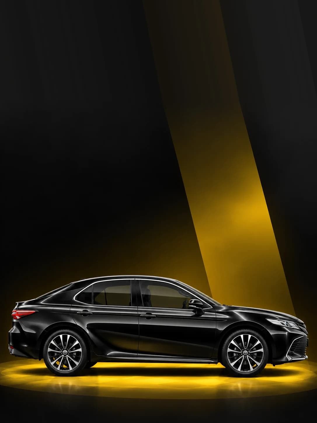 Black Toyota Camry sedan under a yellow spotlight
